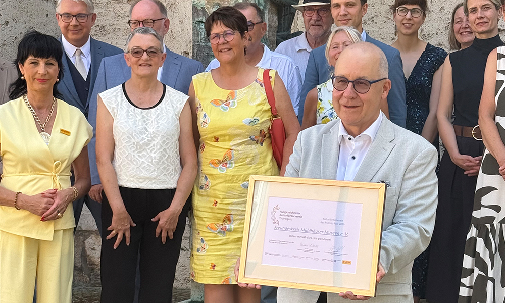 Im Beisein zahlreicher Gäste präsentiert der Vereinsvorsitzende die Auszeichnung stolz der Kamera 
